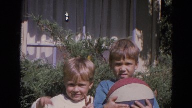 1963: two blond children are holding a big ball while greeting the camera