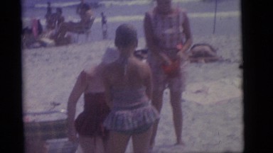 1964: women playing with water bucket on the beach CAMDEN, NEW JERSEY