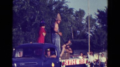 1965: people in costumes riding on the back of a truck in a parade DILLER