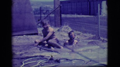 1968: two children playing happily stranded in mud in a courtyard