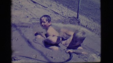 1968: two little boys playing in a self-made puddle. COTTONWOOD, ARIZONA
