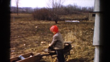 1954: a child in an orange hat playing outdoor with a wheelbarrel OHIO