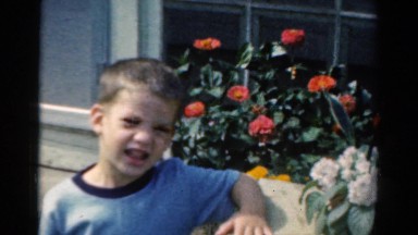 1954: small boy standing next to window box of red and white flowers OHIO