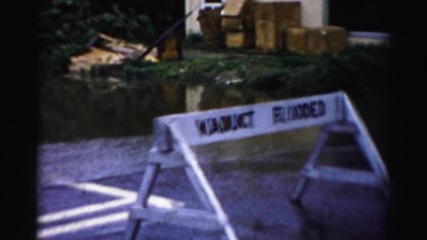 1956: a viaduct slowly overflowing under a railroad bridge on a calm day
