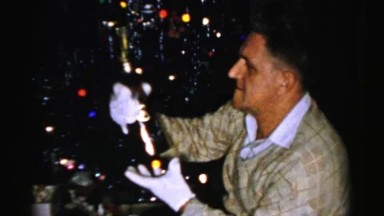 1956: a man wearing white gloves inspecting a bottle in front of a christmas