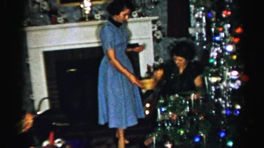 1956: a woman in a blue dress passes a bowl containing refreshments