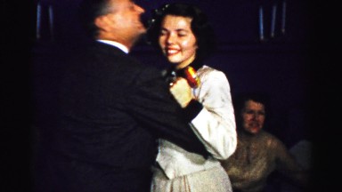1956: ecstatic couple spinning around among friends at a fancy holiday party