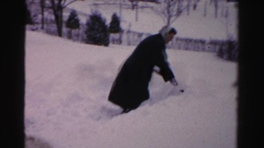 1956: middle-aged woman shoveling deep snow and falling down NEW YORK