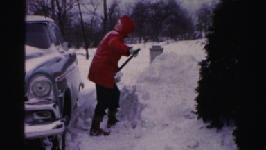 1956: a man dressed with very warm clothes shoveling abundant snow