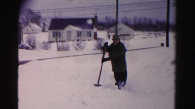 1956: man and woman shoveling snow in their neighborhood in front of their home