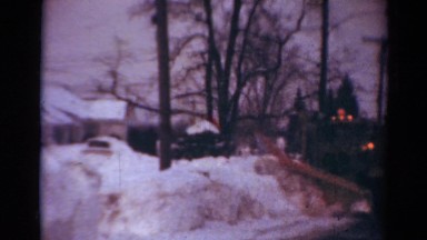 1954: a large snow plowing moving down the street clearing the snow in its path
