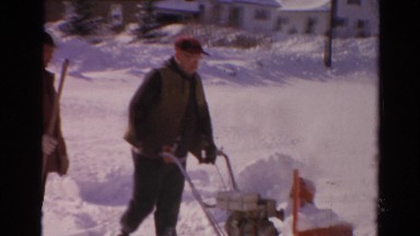 1954: two men removing snow by using a snowblower and shovel. NEW YORK