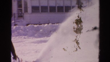 1954: man wearing a hat and warm clothes removing snow