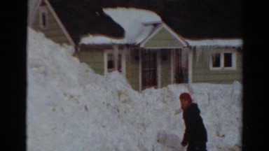 1954: young person stands in front of snow piled high in front of house NEW YORK