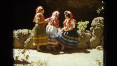 1962: three women in traditional dress talking at the edge of a grotto MEXICO