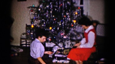 1959: various people inside, gathered around a decorated christmas tree