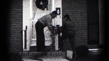 1959: a pair of people decorating the front of their house with ornaments