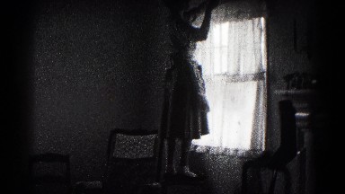 1959: woman in an apron hanging christmas decorations on a window frame