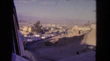 1962: old buildings, with desert and mountains in the background seen from a car