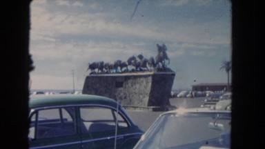 1962: statues, cars, and people fill the parking area outdoor a stadium