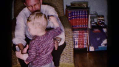 1959: two small children eagerly come to sit on daddy's knee after he returns