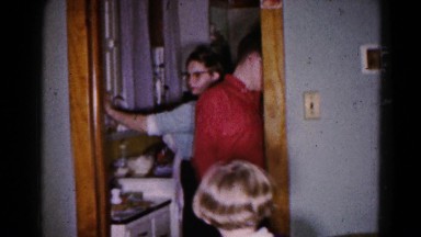 1959: a family is busy preparing dinner and a boy points out his infant sibling