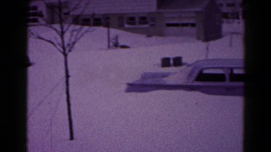 1959: people try to shovel a thick snow from a parking lot and parked cars