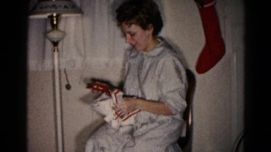 1959: unwrapping gift woman sitting indoor HAGERSTOWN, MARYLAND