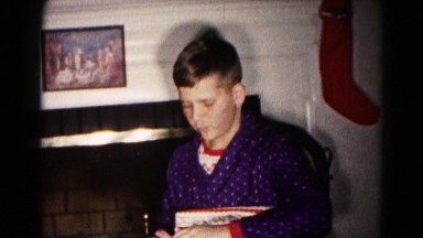 1959: a young boy opening and inspecting one of her presents in christmas