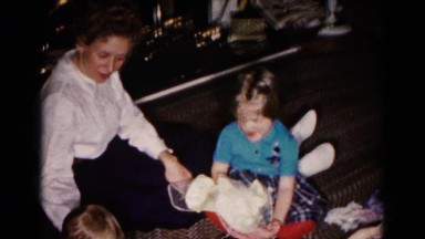1959: a little girl and a baby inside on the floor playing as their mother looks