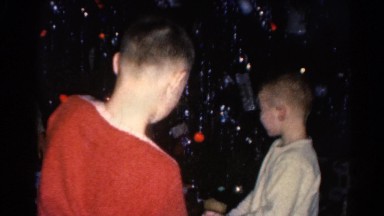 1962: Children Playing With Model Train and Toy Shopping Cart at Christmas Tree Base