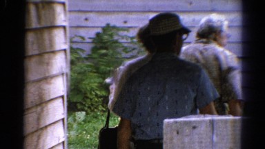1962: two men and a woman walking past a rustic wooden house CATSKILL, NEW YORK