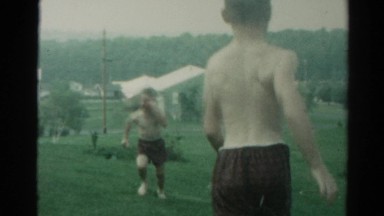 1962: mother is holding a hose spraying water and the boys run through it