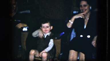 1951: a woman and child seated inside with presents stacked behind them