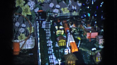 1951: a toy train village and tracks displayed underneath a christmas tree