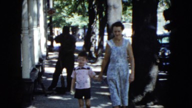 1951: mother and child holding hands walking down sidewalk