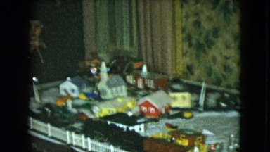 1951: child watching a miniature train that is working on a white table around