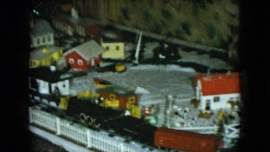 1951: a miniature train circling around christmas gifts under a tree. CLEVELAND
