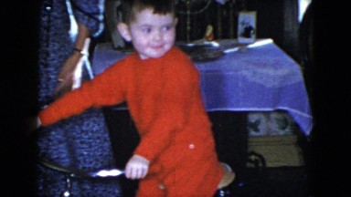 1951: small child sitting on a bicycle inside a living room. CLEVELAND, OHIO