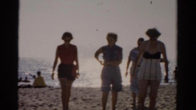 1957: ladies in old-fashioned swimsuits are walking back from the ocean