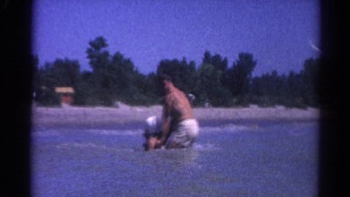 1962: a man pulling a girl through the water, then lifts her up and throws her