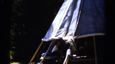 1962: various people and boys in yellow shirts gathered under a darkly lit