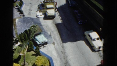 1962: large buildings on a hill with many vehicles parked in the surrounding
