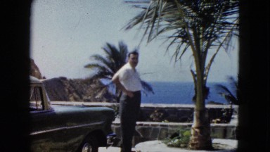 1962: a man walking around his car while enjoying the breeze