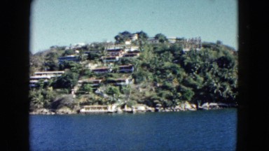 1962: a beautiful view of homes on the coastline as seen from a moving vessel