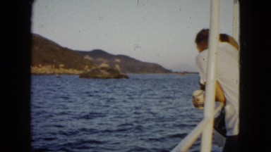 1962: a crowd of people on a small boat enjoy the view as they sail past rock