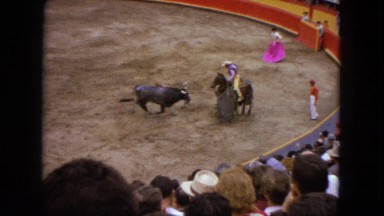 1962: a bull fighting a lancer on horseback during a bullfight at large audience