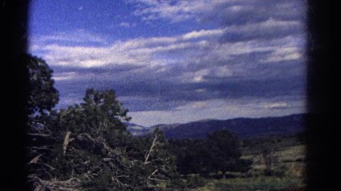 1967: driving past mountains and evergreens on a sunny day. COLORADO