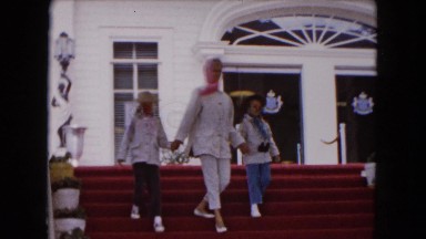 1961: Woman in Scarf Walking Down Building Steps Holding Hands with Two Girls