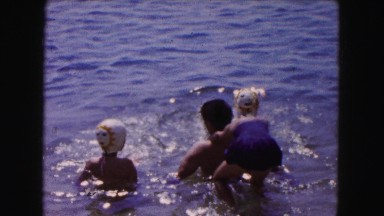 1961: kid playing in shallow water with adults and another child MINNESOTA